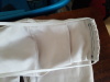 Closeup 2 A close shot of a white Olson mask showing black stitching holding the elastic down and white stitching on the area where the filter can be inserted